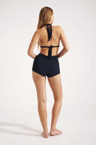 Woman wearing a black bikini halter top and shorts on a white background