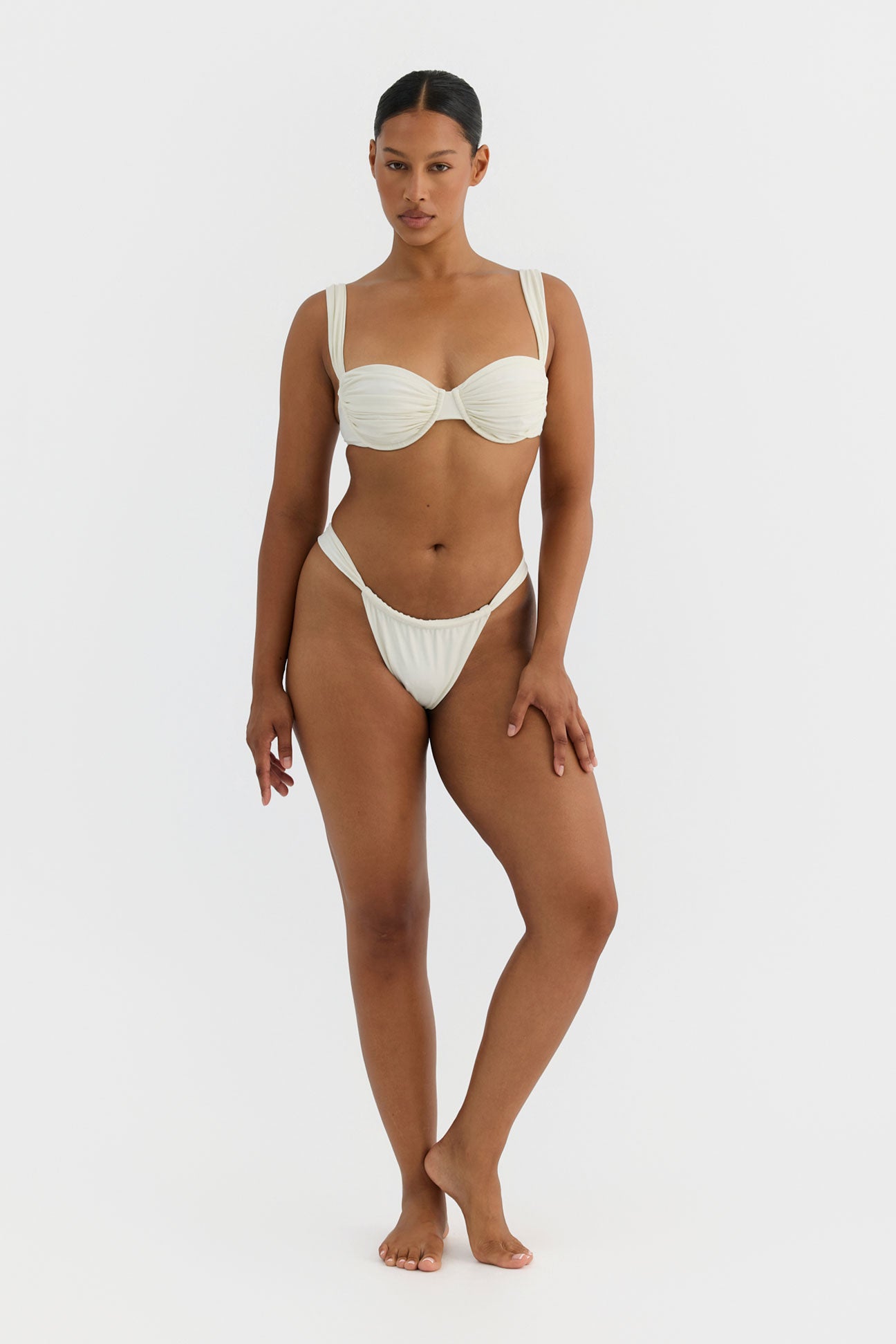 Woman wearing a white bikini on a light gray background