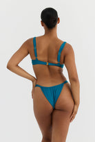 Woman wearing a teal bikini on a white background