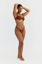 Woman wearing a terracotta bikini on a white background