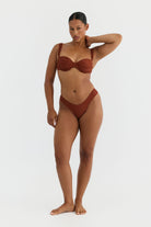 Woman wearing a terracotta bikini on a white background