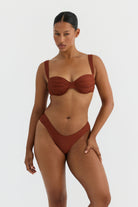 Woman wearing a terracotta bikini set on a white background
