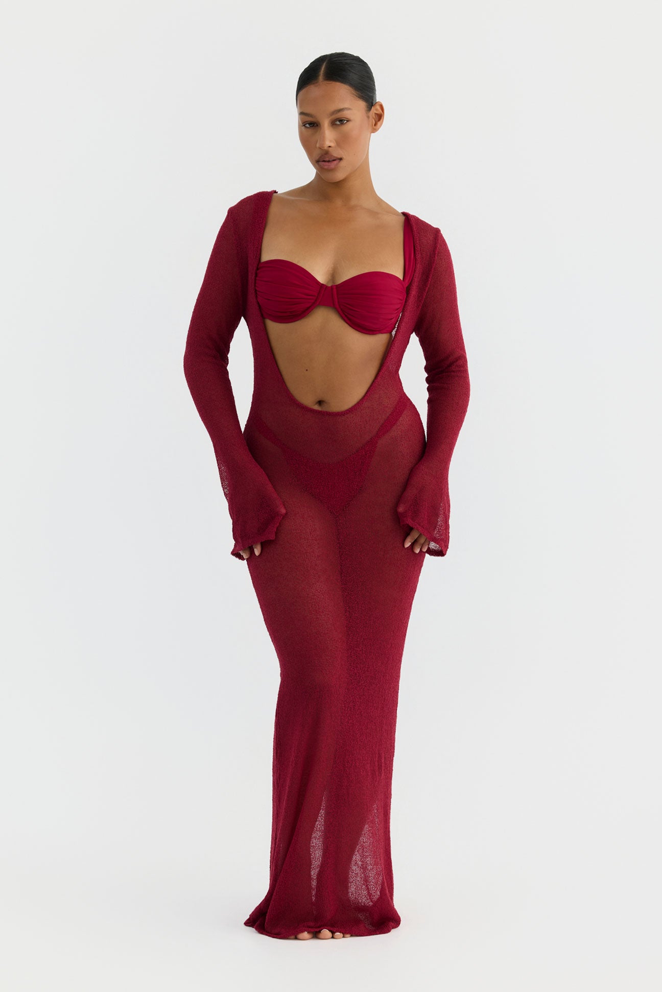 Woman wearing a magenta dress with cut-out design on a white background