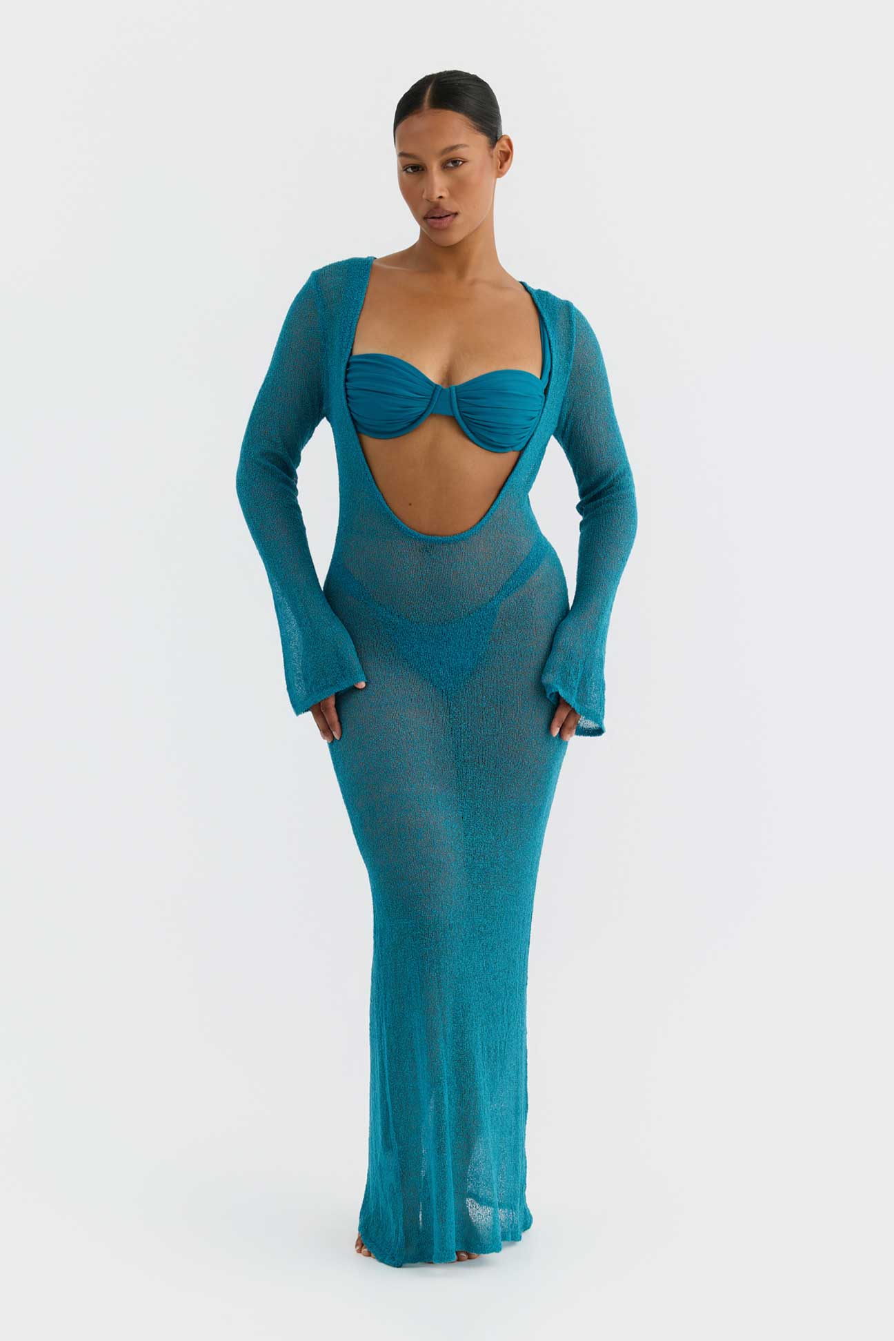 Woman wearing a teal dress with cut-out design on a white background