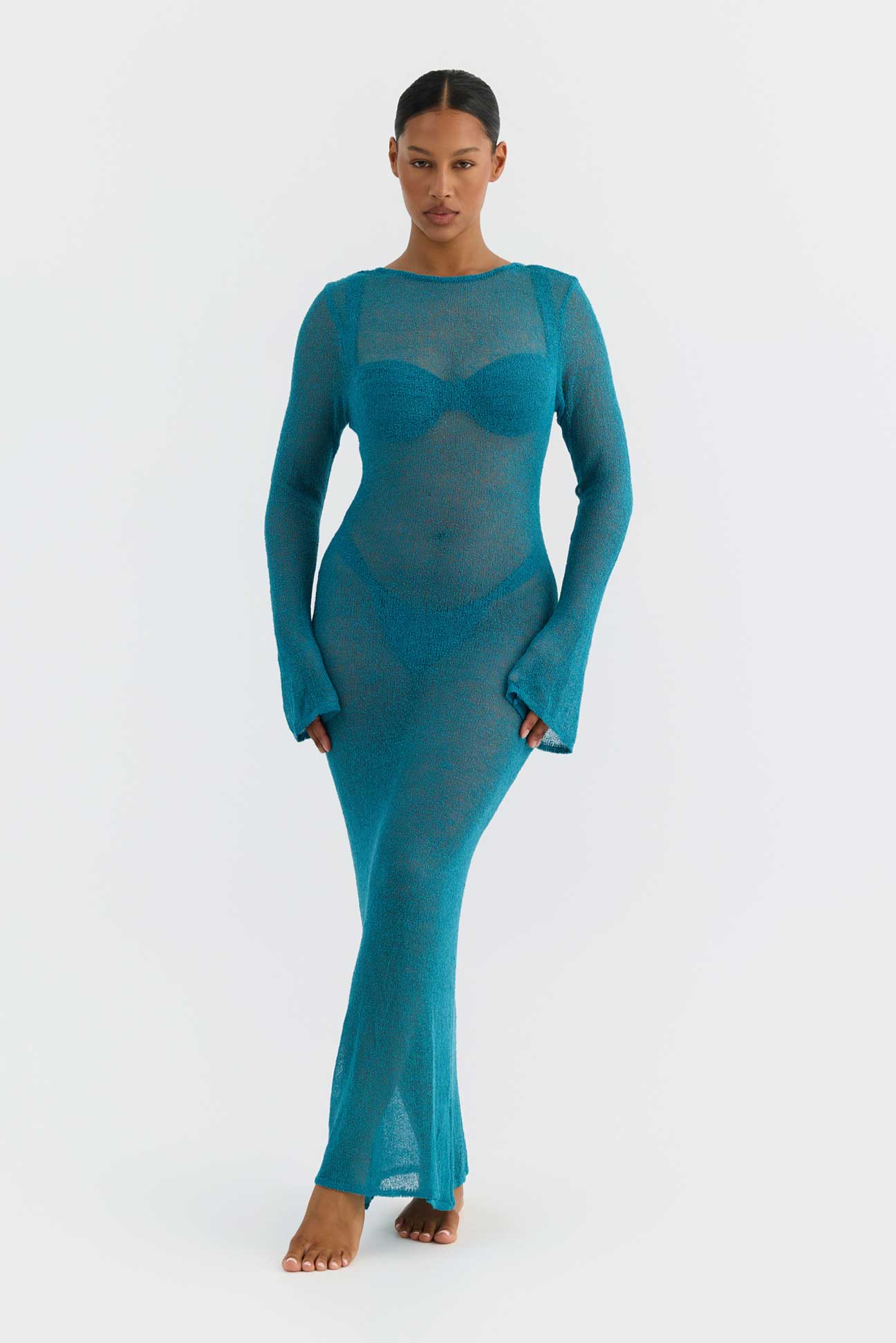 Woman wearing a teal sheer dress on a white background