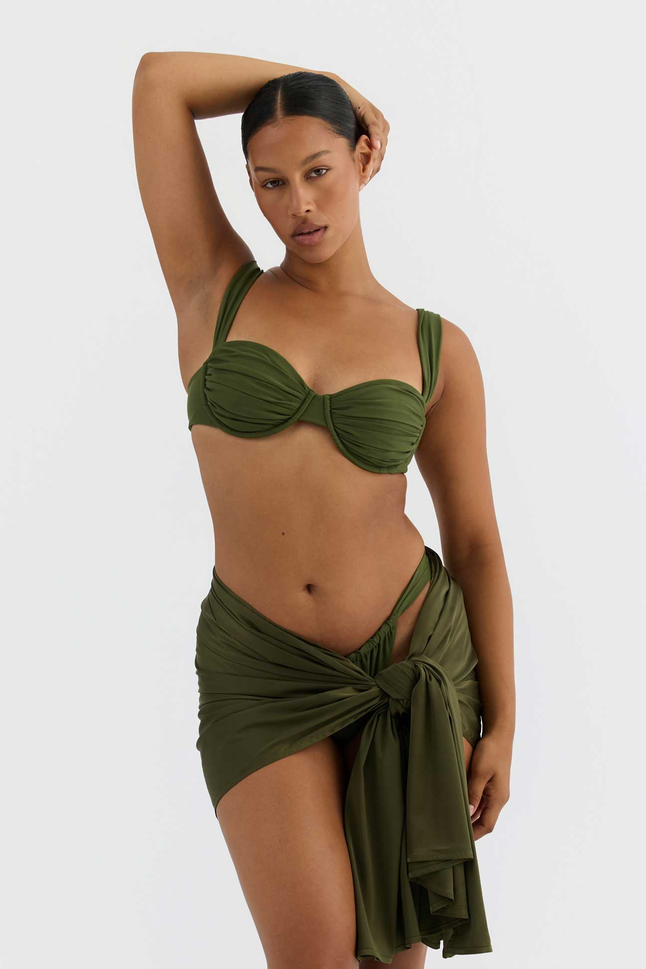 Woman wearing a green bikini with a matching wrap on a white background