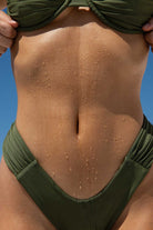 Person wearing a green bikini against a clear blue sky