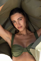 Woman wearing a green bikini top lying on a green cushioned surface.