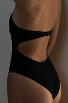 Black swimsuit with cut-out design on a neutral background
