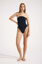 Woman wearing a black strapless swimsuit on a white background