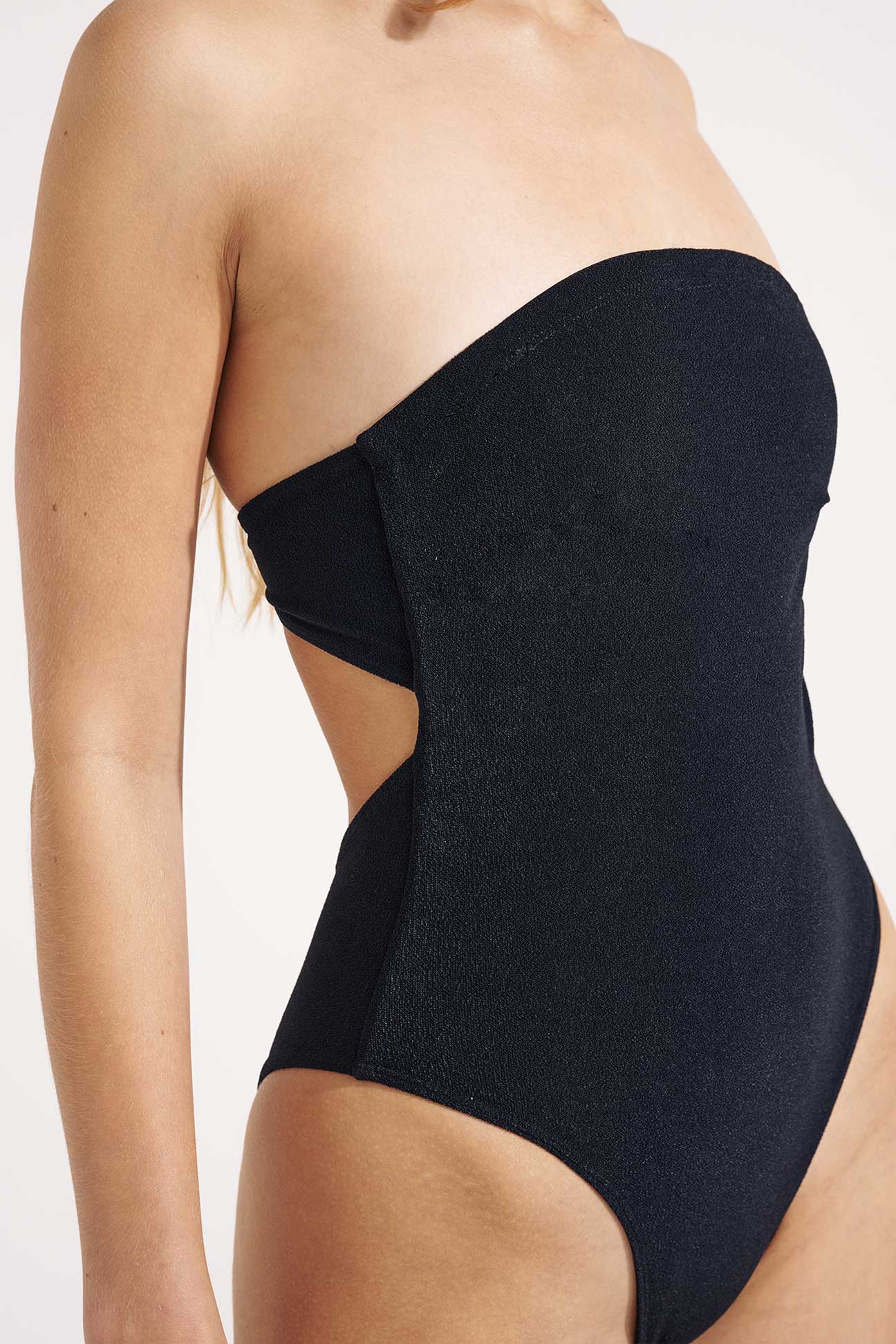 Black one-shoulder swimsuit with cutout design on a white background