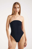 Woman wearing a black strapless swimsuit on a white background