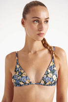 Woman wearing a floral bikini top against a plain background