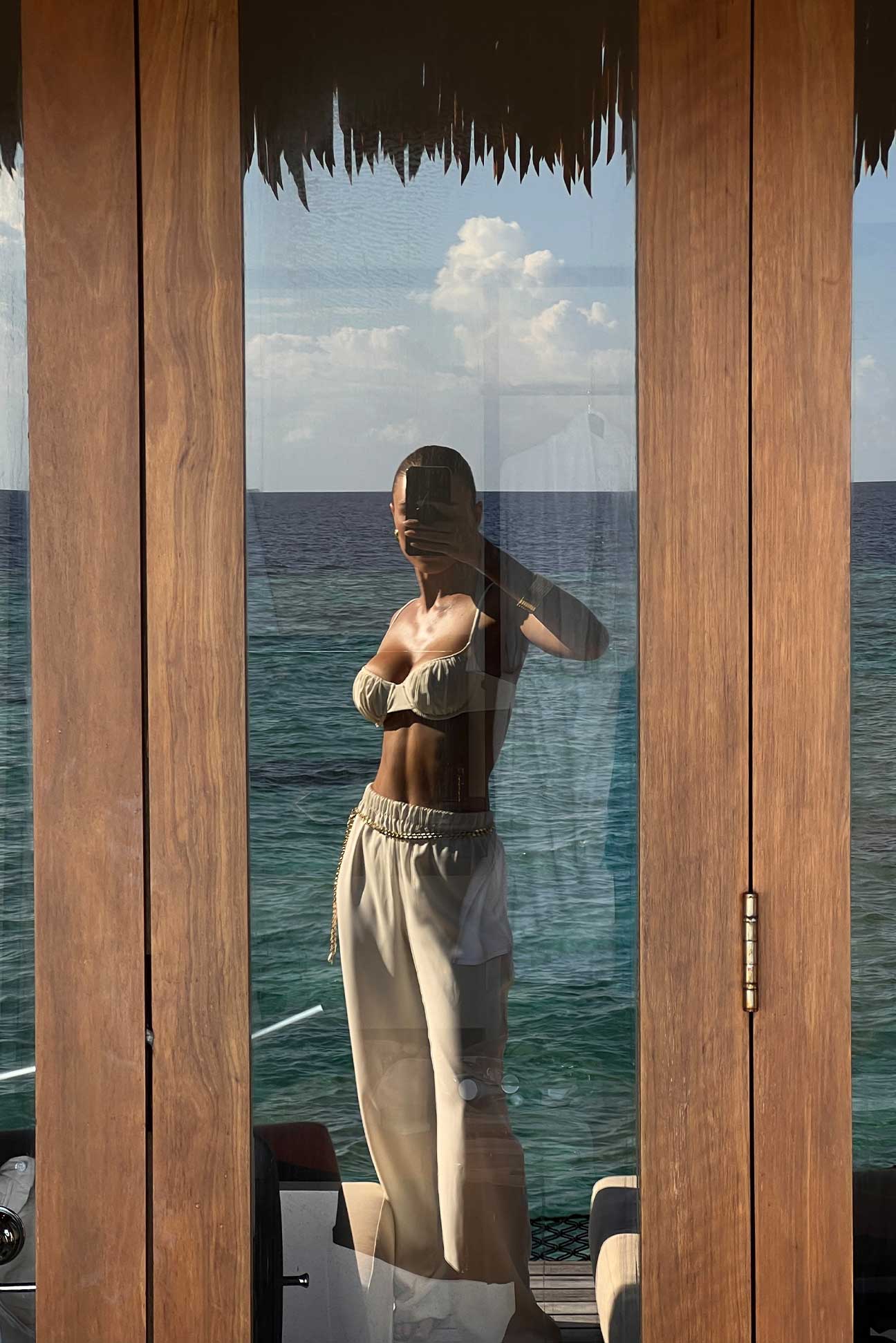 Woman standing by a wooden structure with a view of the ocean.