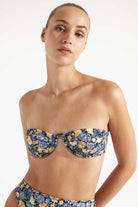 Woman wearing a floral bandeau bikini against a white background