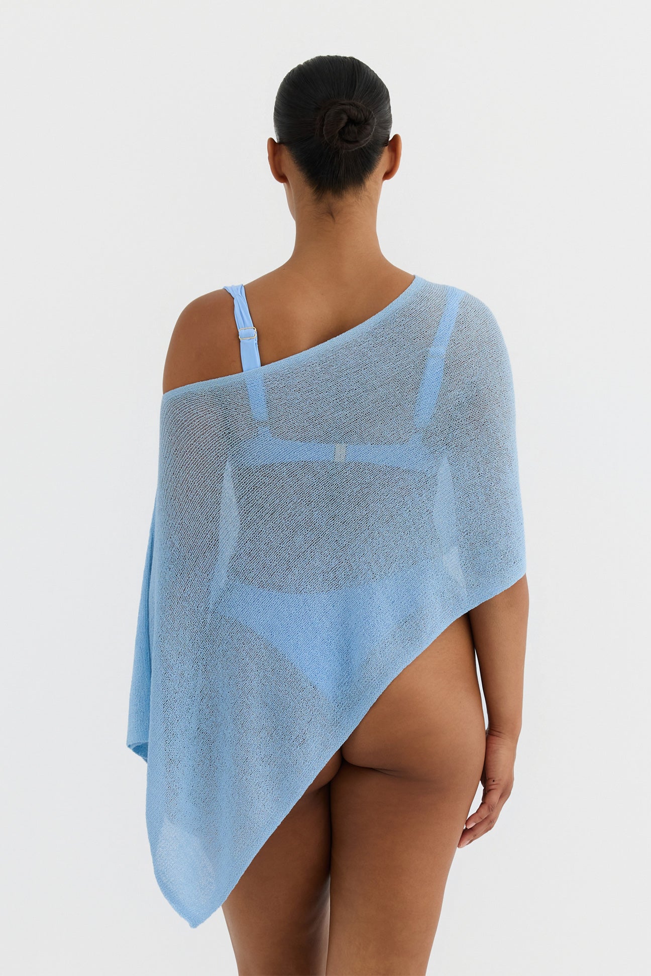 Person wearing a light blue knit poncho on a white background
