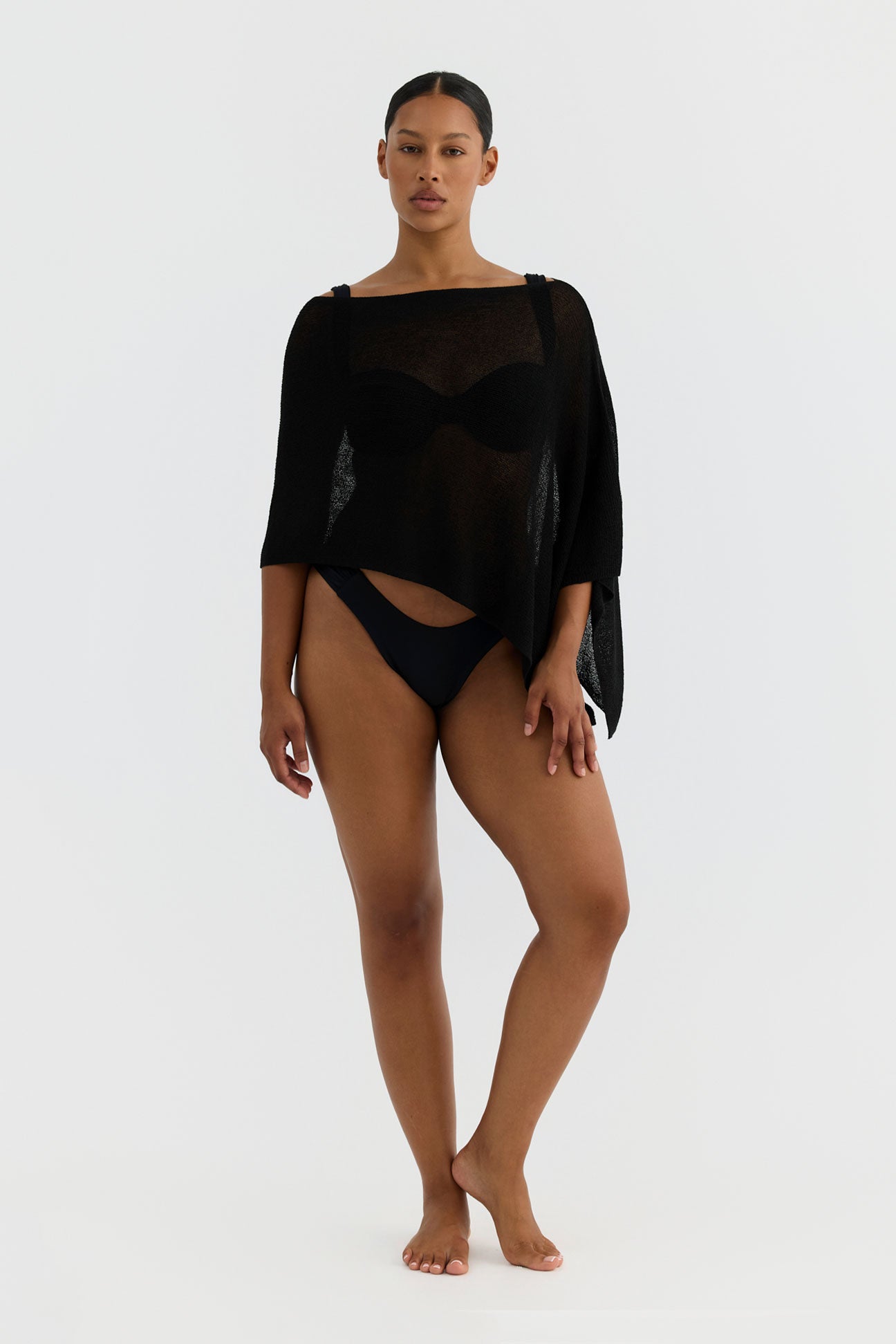 Woman wearing a black swimsuit with a sheer overlay on a white background