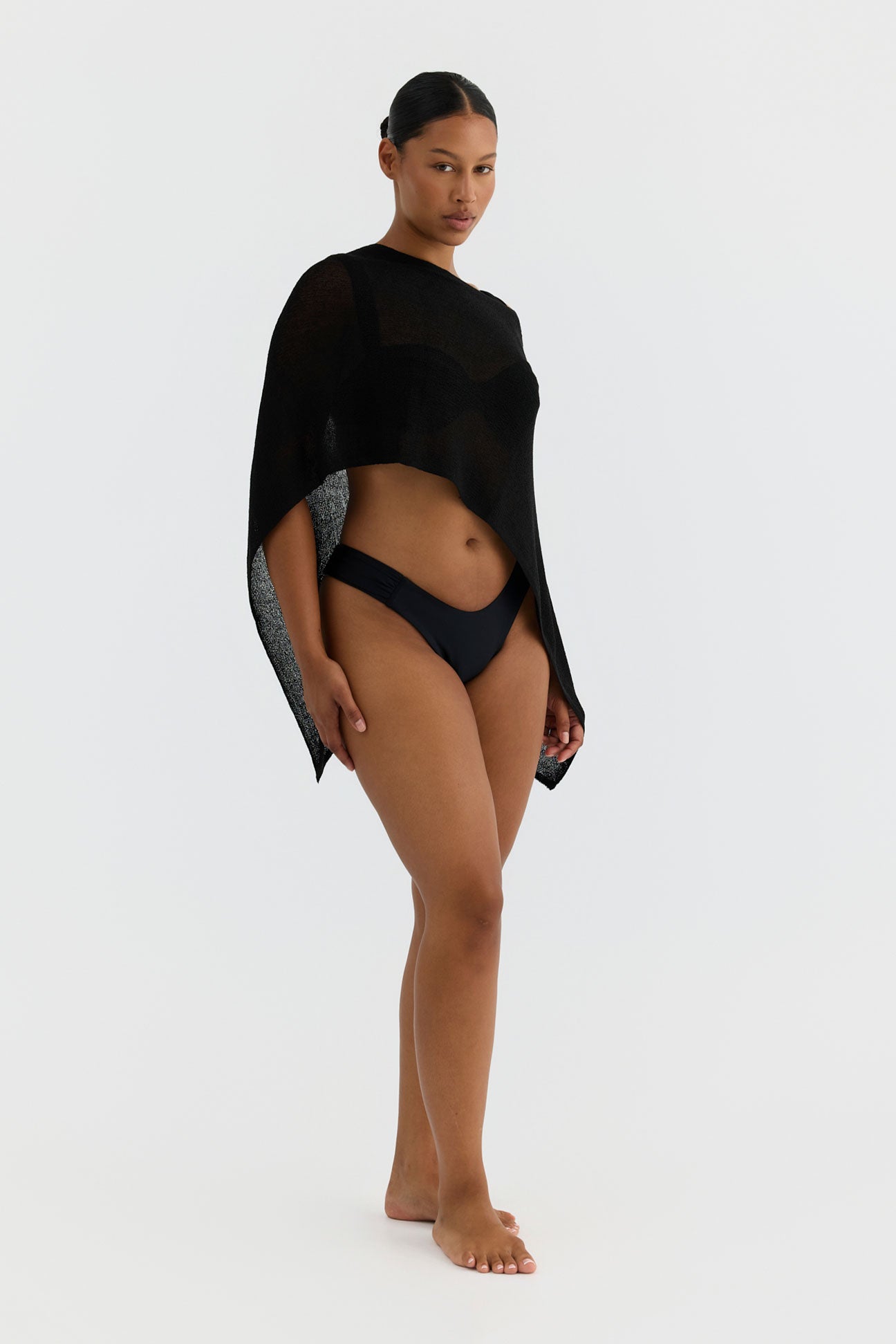 Woman wearing a black swimsuit and cover-up on a white background
