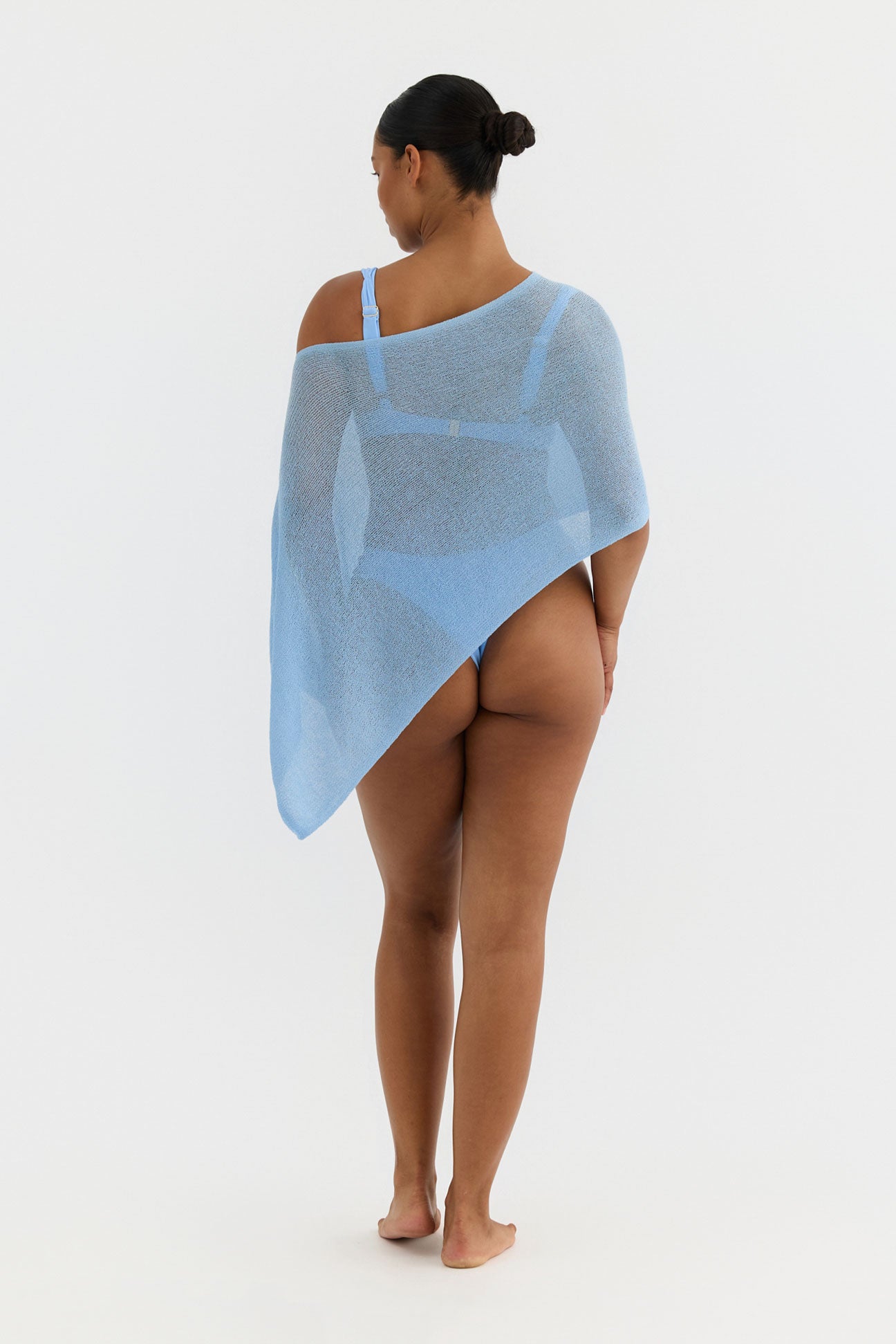 Person wearing a light blue poncho on a white background