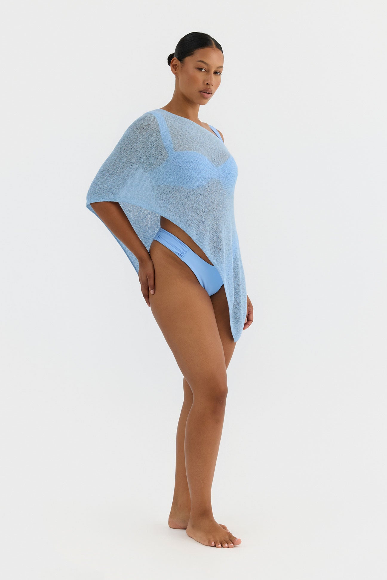 Woman wearing a light blue poncho on a white background