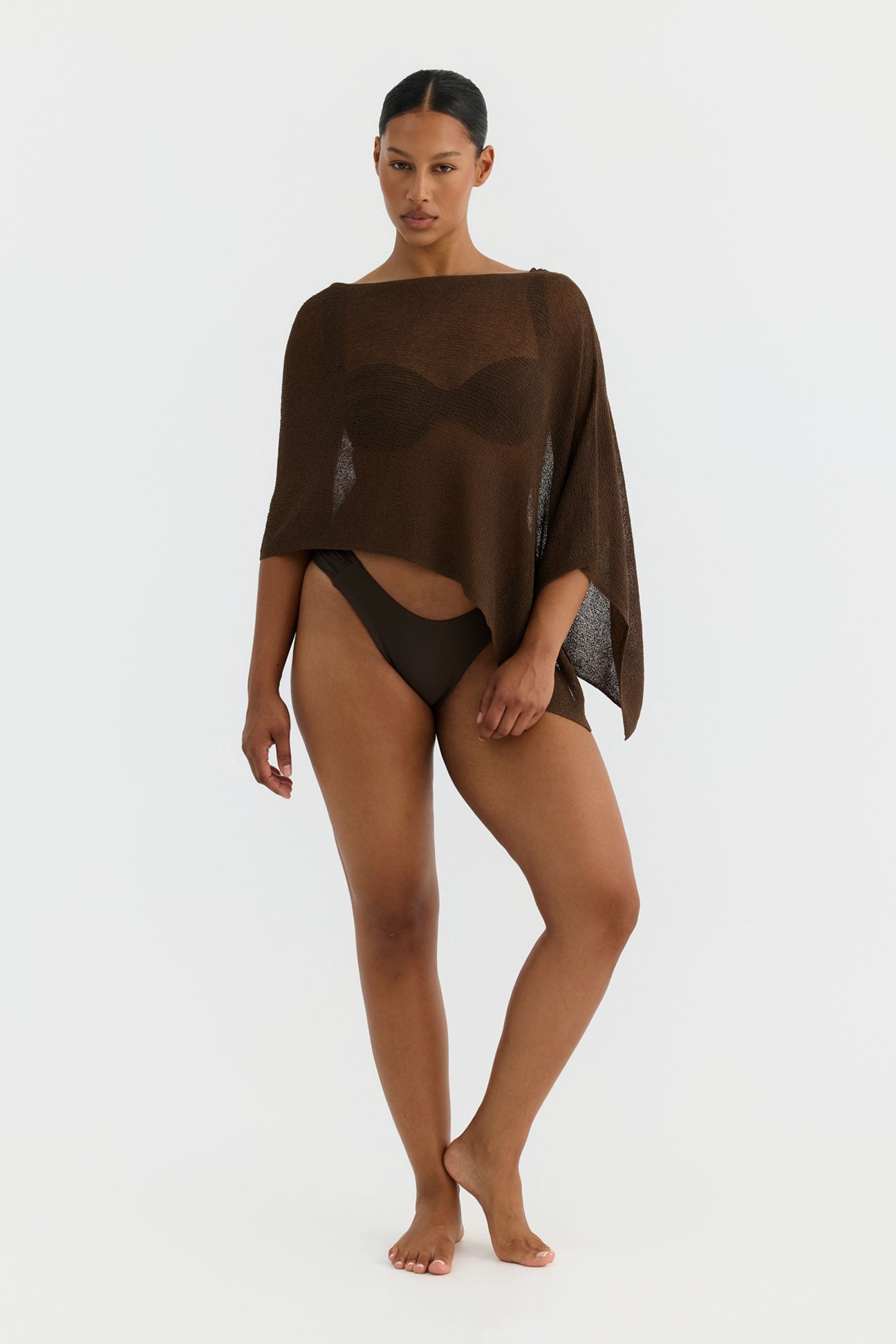 Woman wearing a brown poncho over a brown swimsuit on a white background