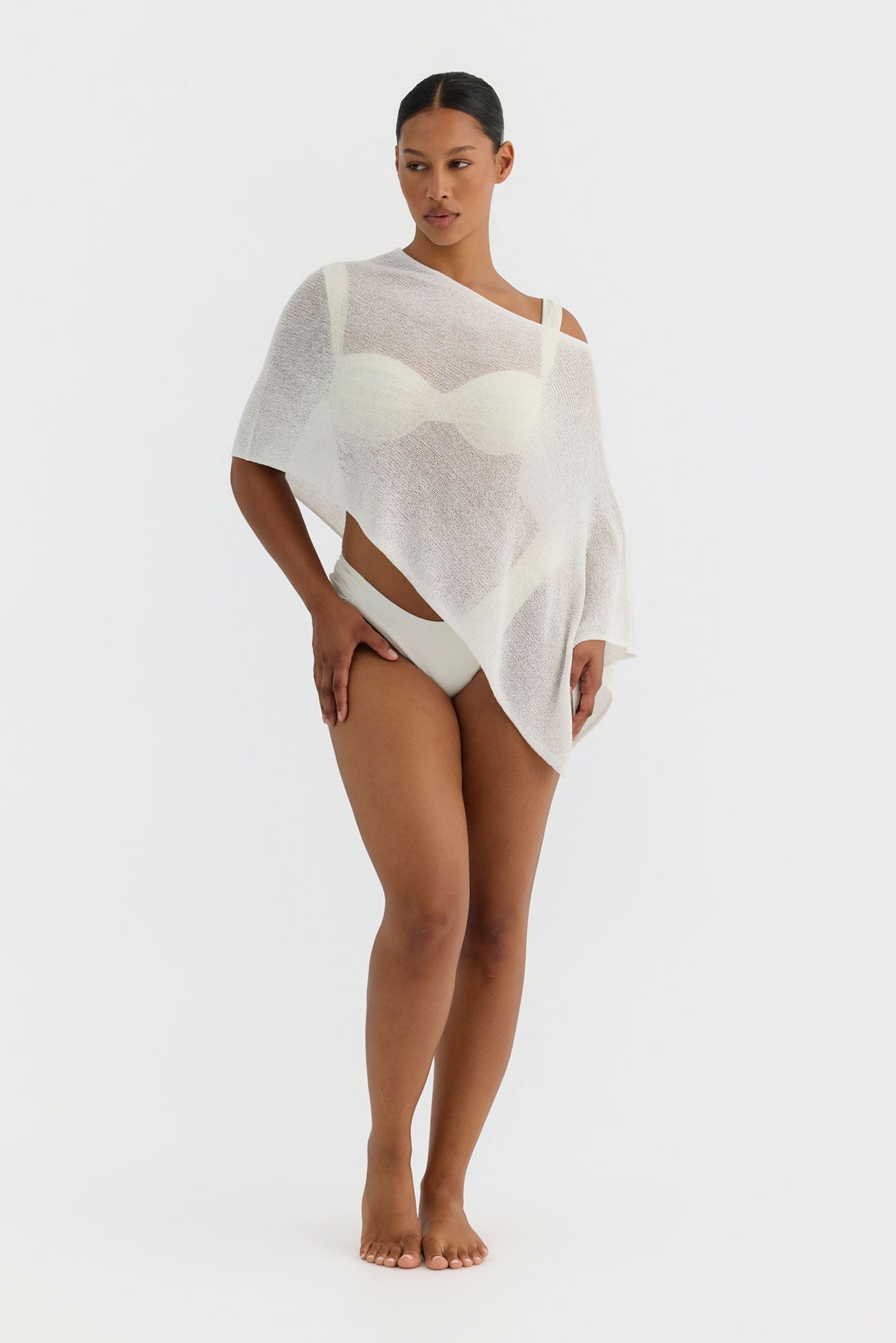 Woman wearing a white poncho against a plain background