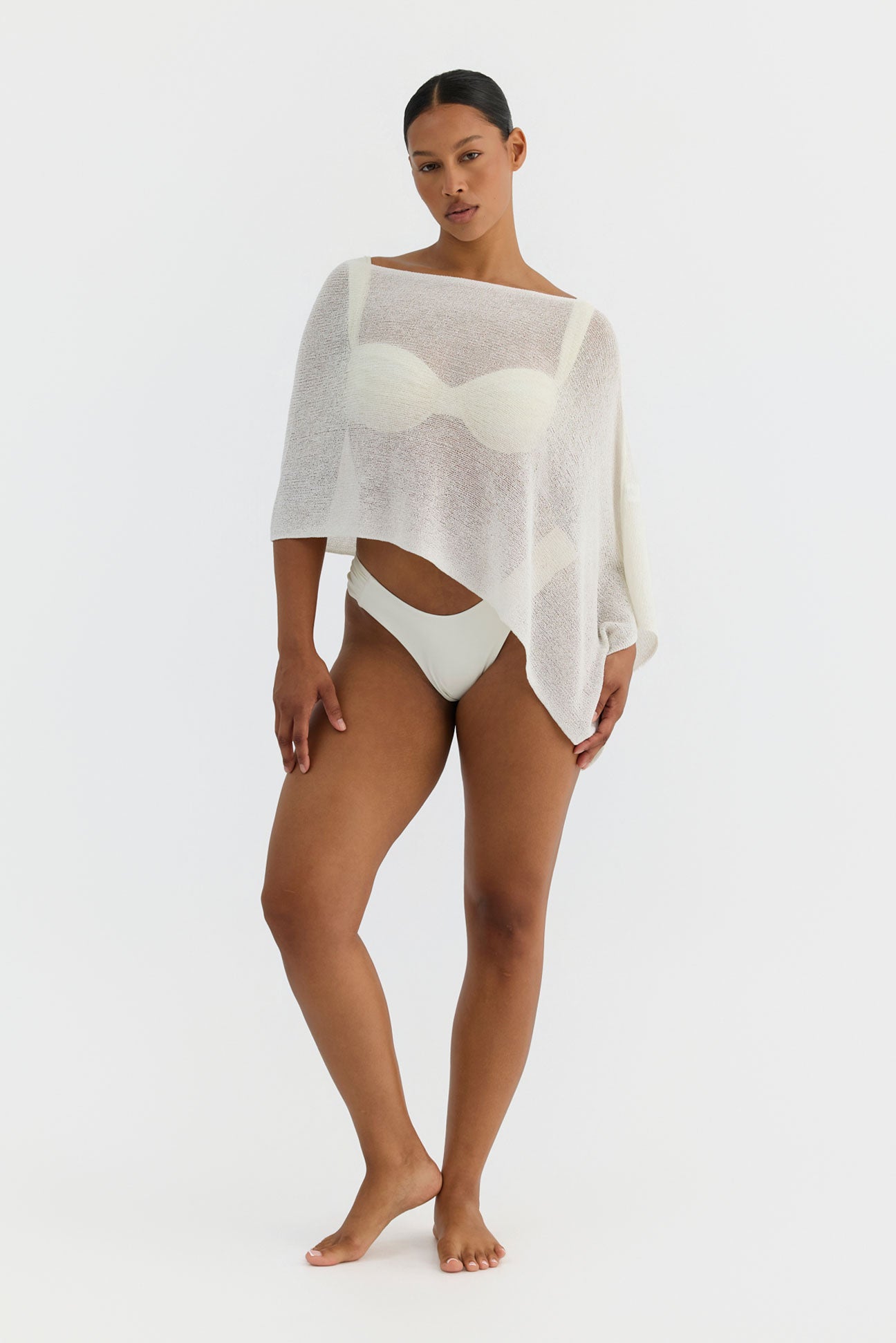 Woman wearing a sheer white cover-up over a swimsuit on a white background