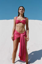 Woman wearing a pink bikini and sarong on a sandy background