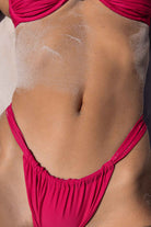 Person wearing a pink swimsuit with sand on their back