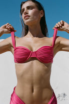 Woman wearing a pink bikini against a clear blue sky.