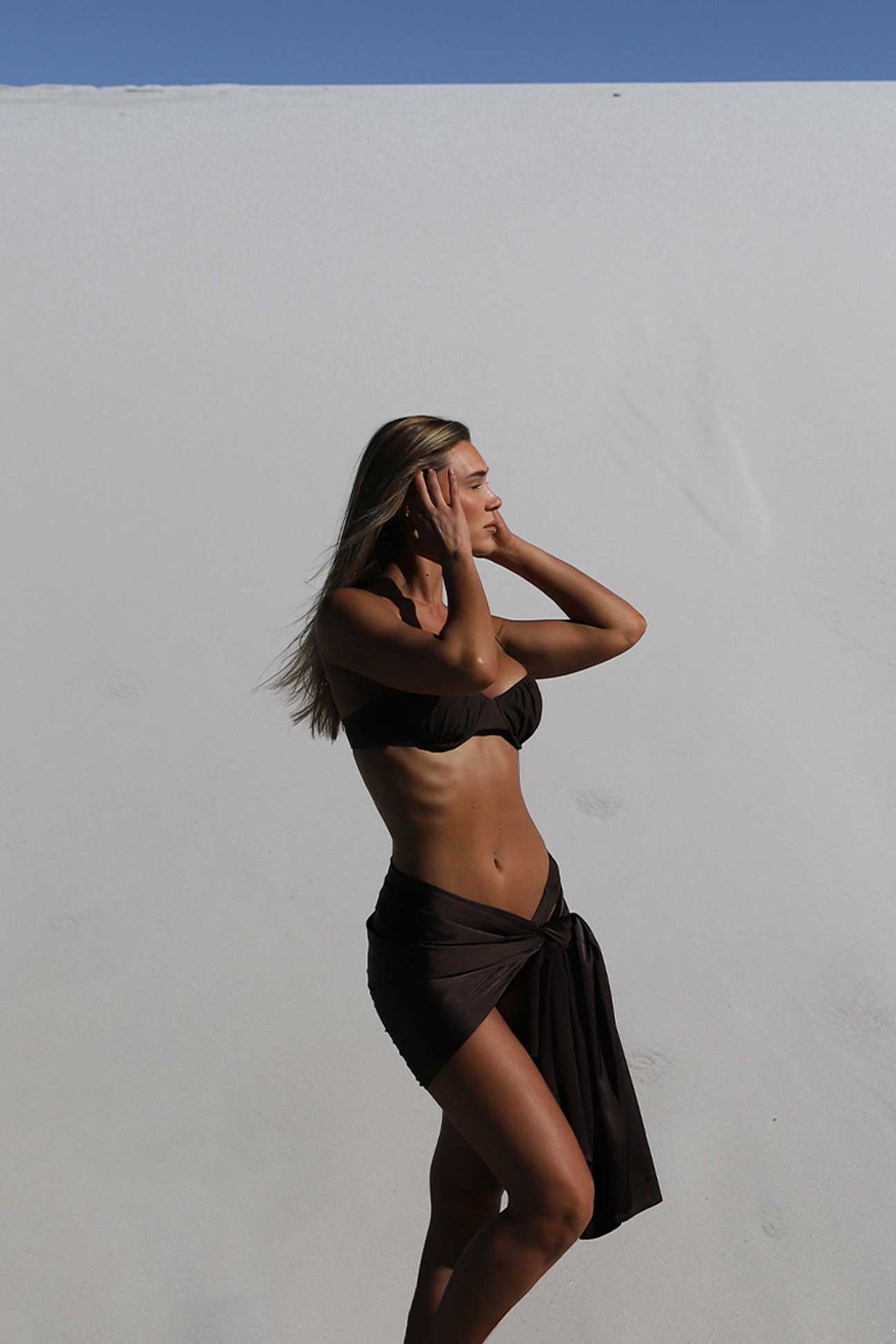 Person wearing a brown bikini with a matching wrap on a plain background