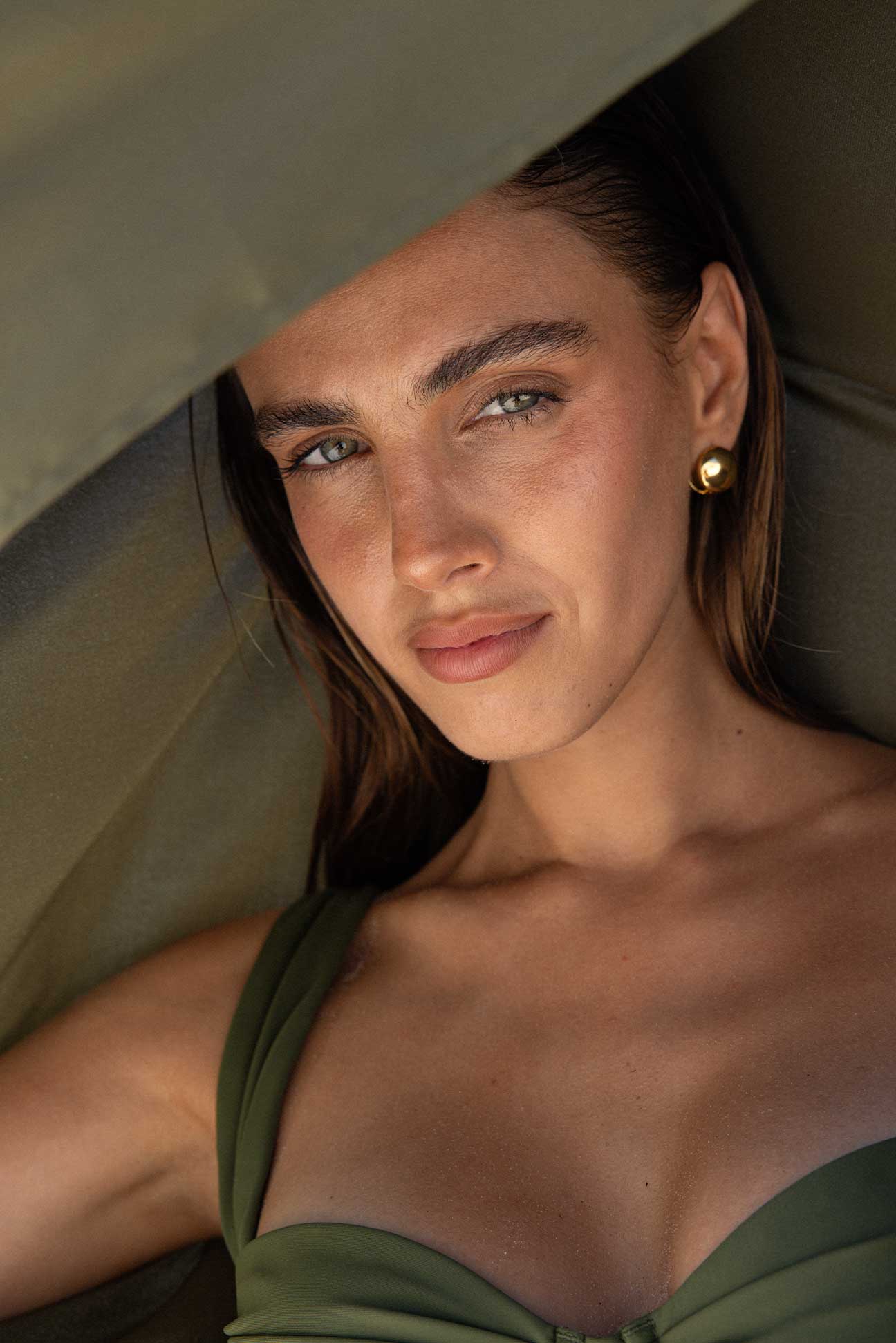 Woman wearing a green cover up and bikini with a blurred background