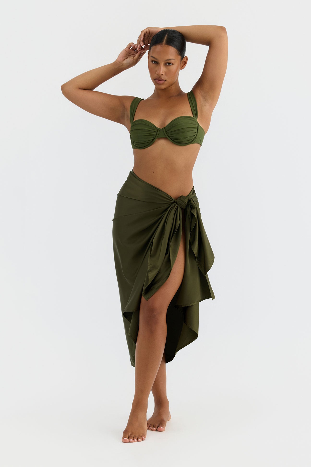 Woman wearing a green bikini with a matching wrap skirt on a white background