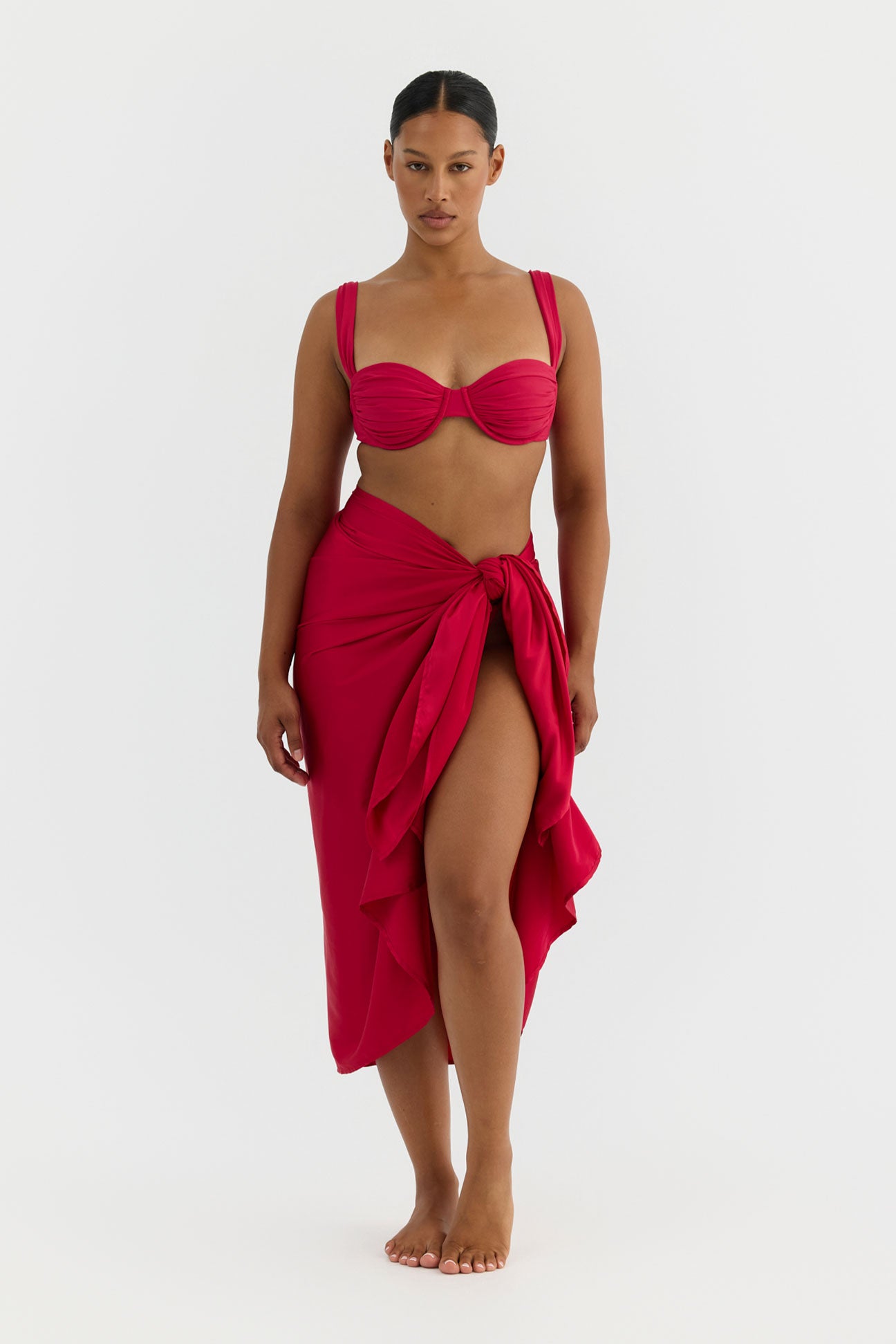 Woman wearing a red bikini and matching sarong on a white background