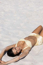Woman in a yellow bikini lying on a sandy beach