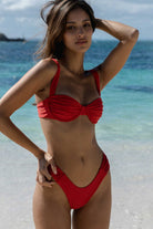 Woman in a red bikini standing on a beach with ocean in the background