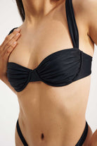 Black bikini top worn by a person on a white background