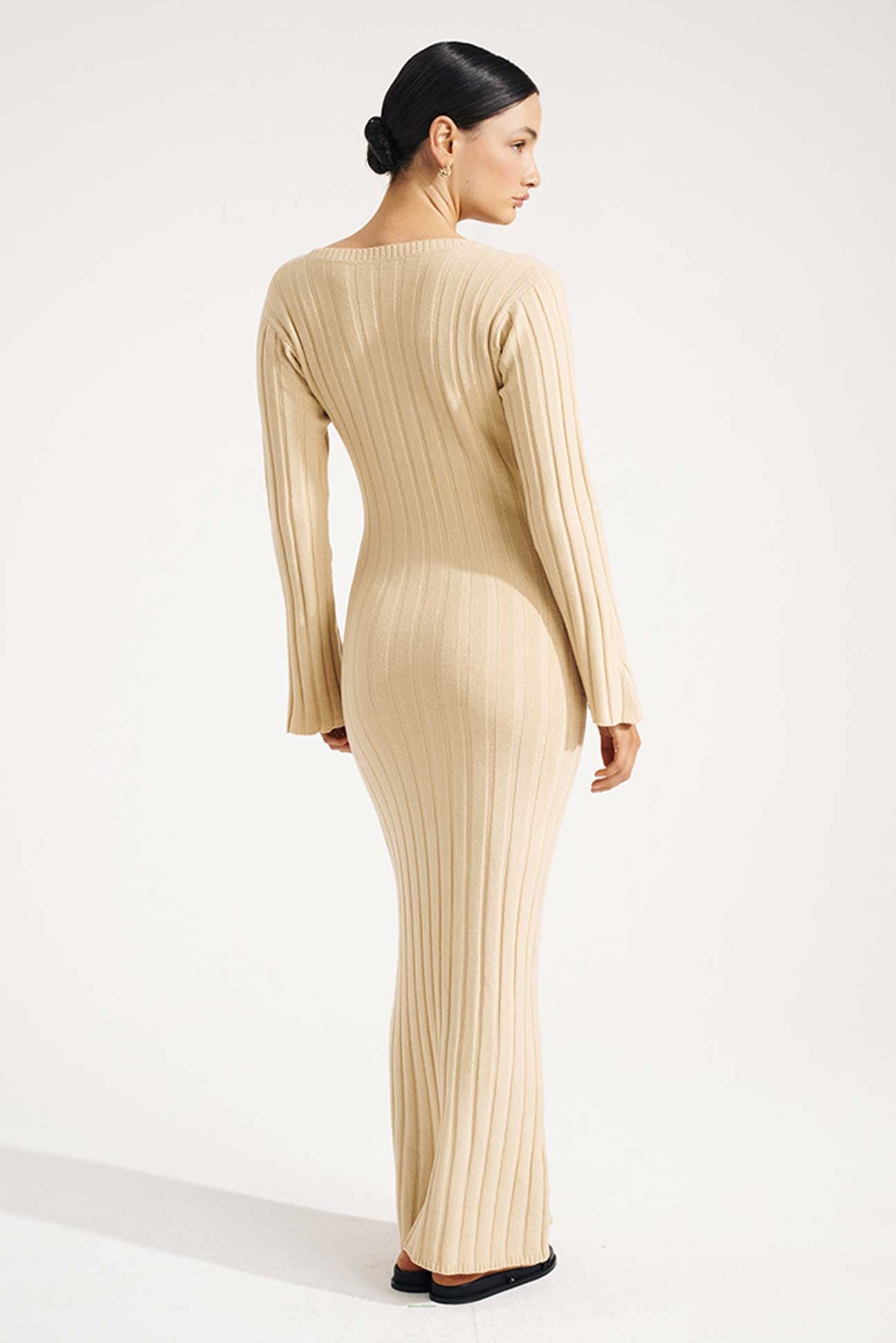 Woman wearing a beige ribbed dress on a white background