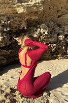Woman in a magenta dress sitting on a rocky beach