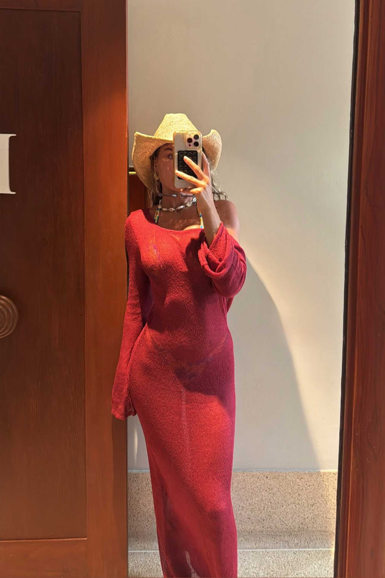 Person wearing a magenta dress and hat taking a mirror selfie.