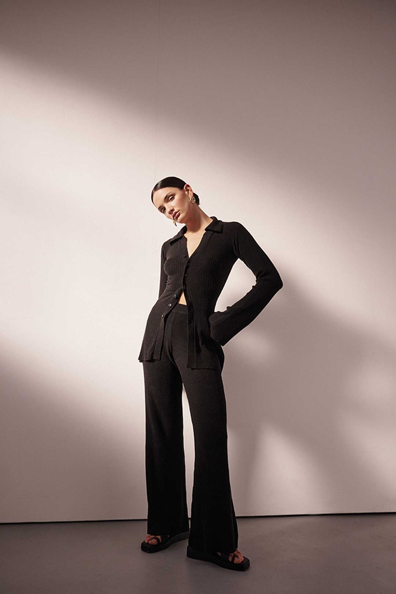 Woman wearing a black suit standing against a plain background