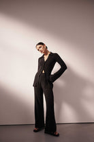 Woman wearing a black suit standing against a plain background