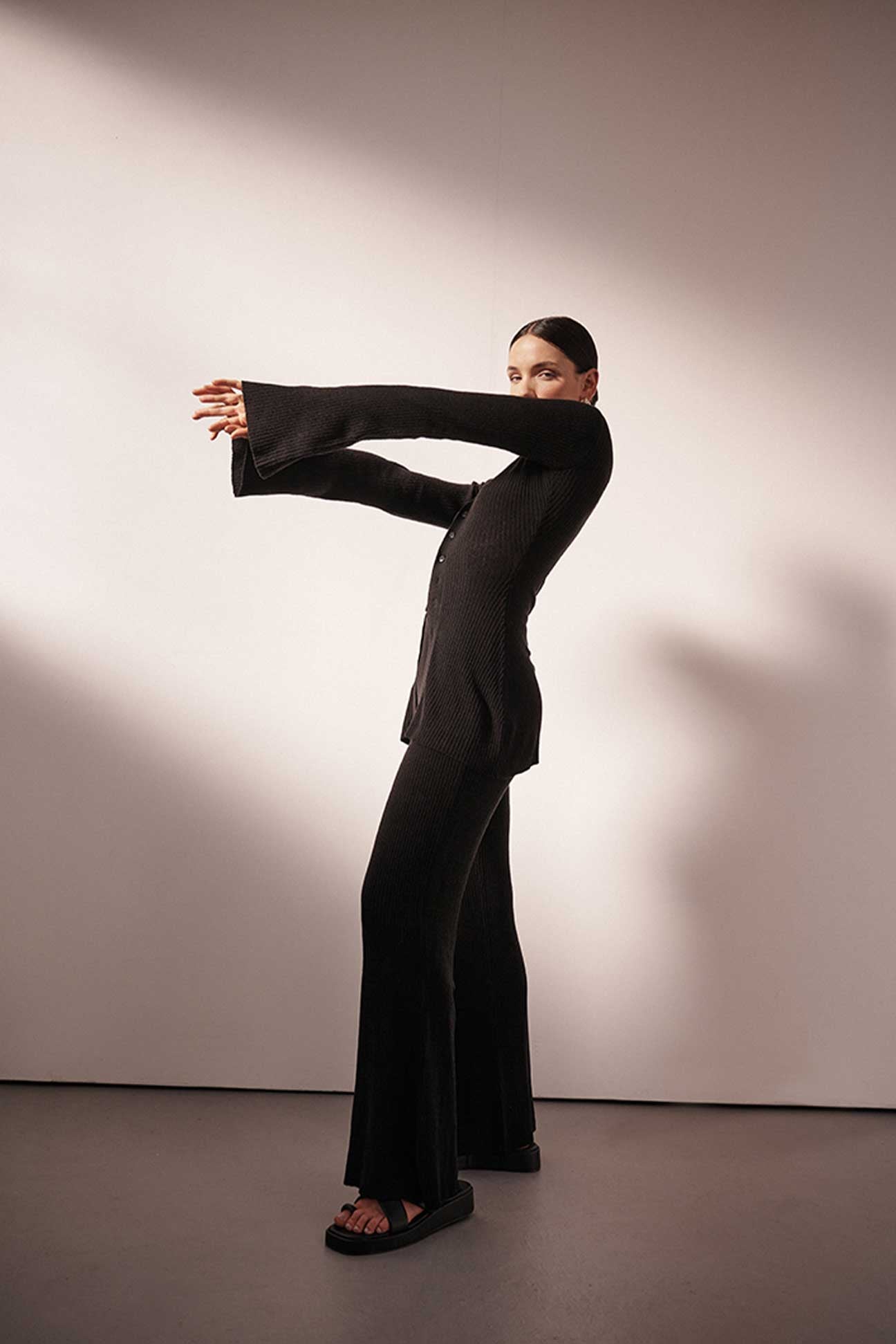 Person wearing a black outfit posing against a plain background