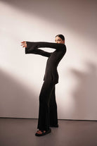 Person wearing a black outfit posing against a plain background