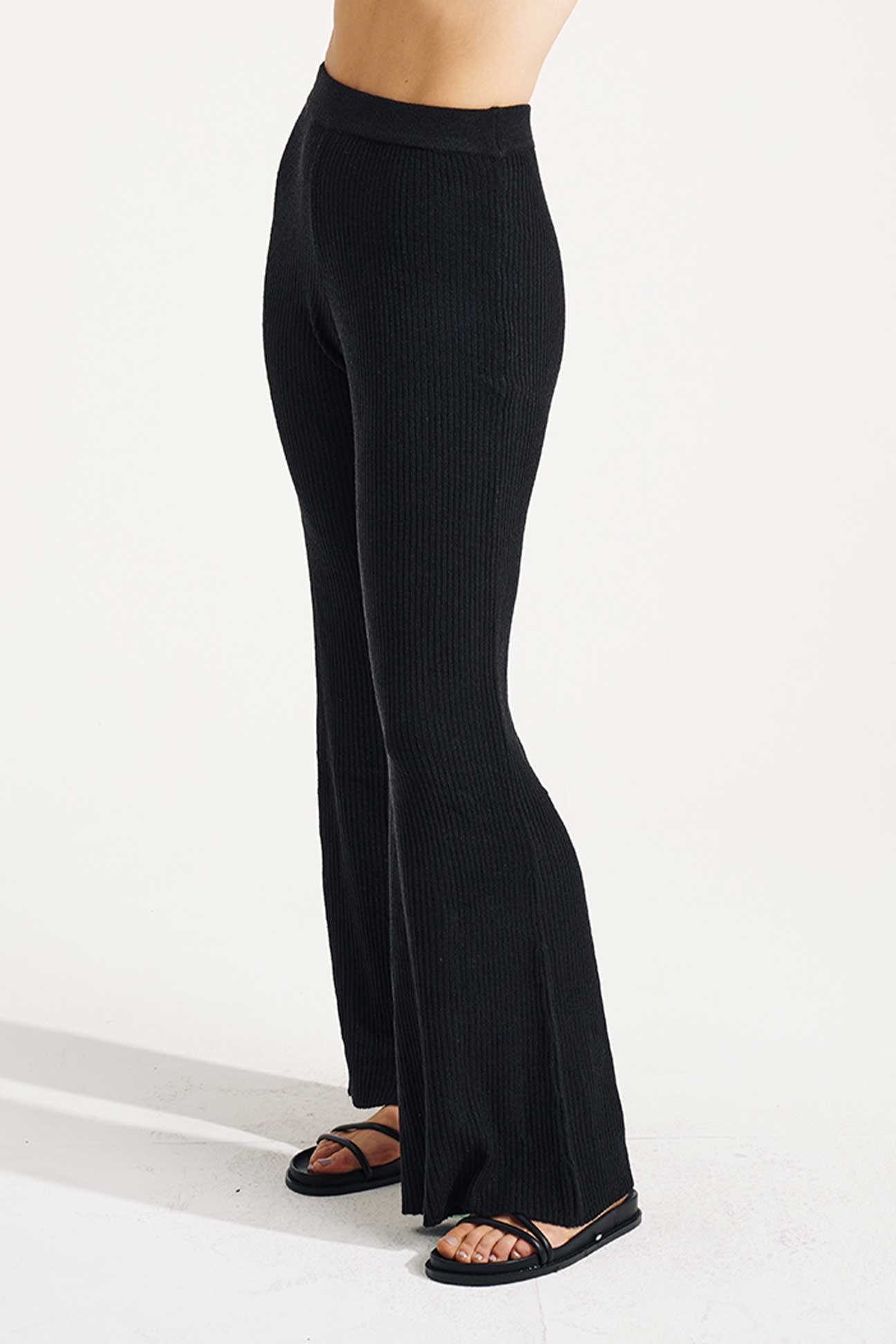 Black ribbed flared pants worn by a person on a white background