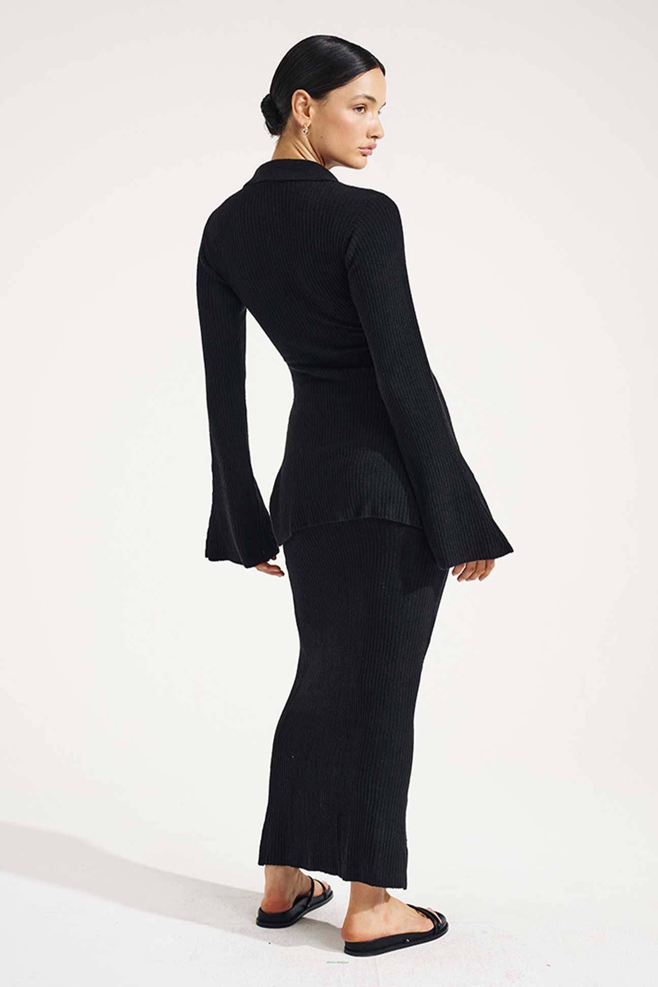 Woman wearing a black outfit with bell sleeves on a white background