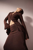 Person wearing a brown ribbed outfit against a plain background