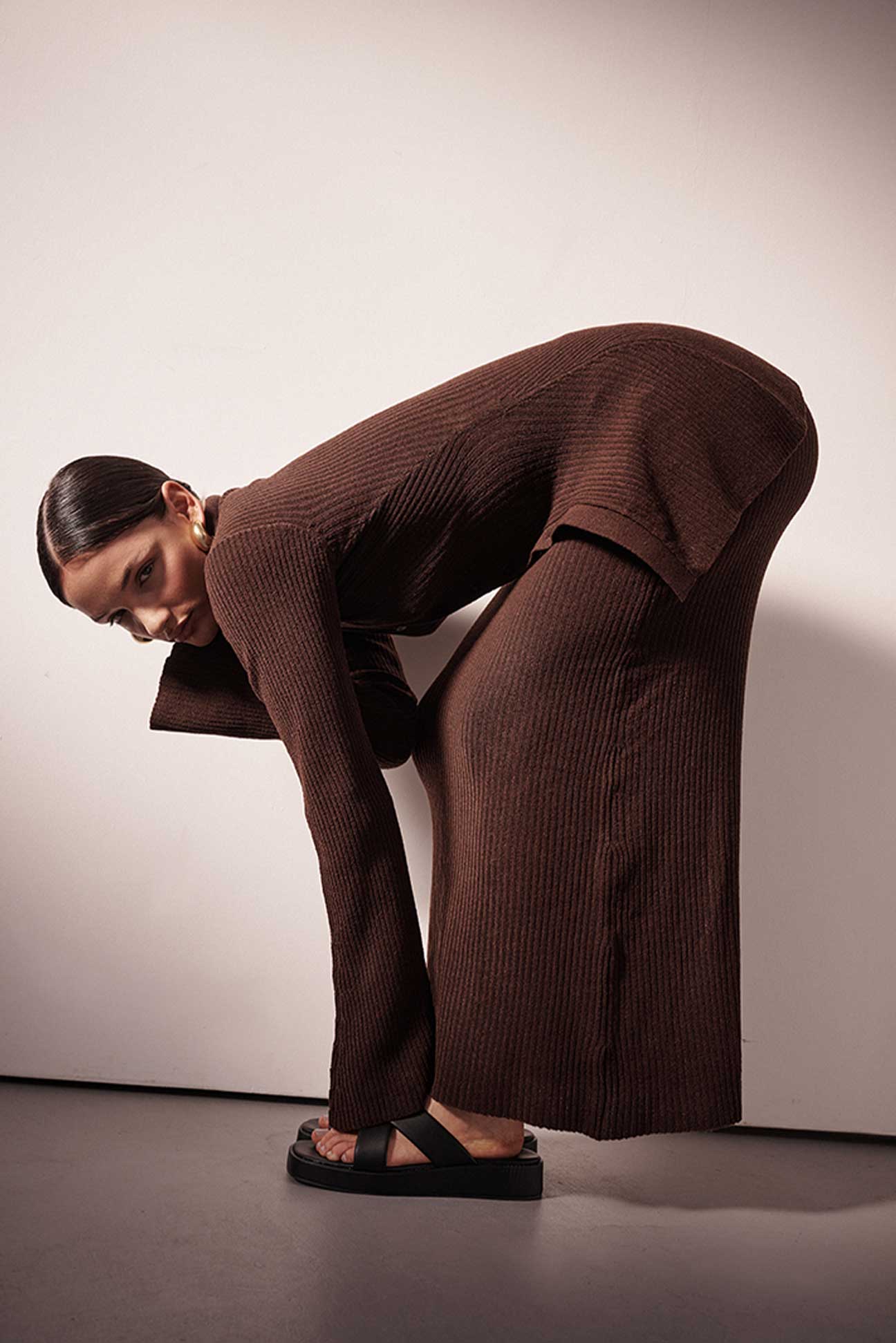 Person wearing a brown outfit posing against a plain background
