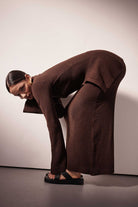 Person wearing a brown outfit posing against a plain background