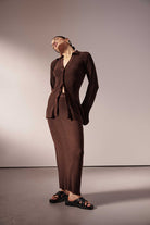 Woman wearing a brown ribbed skirt and top against a plain background